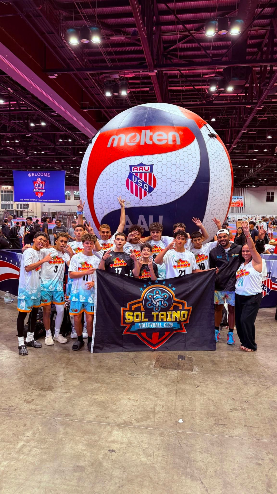 Equipo Sol Taíno posando con la bandera del club frente al balón gigante del AAU