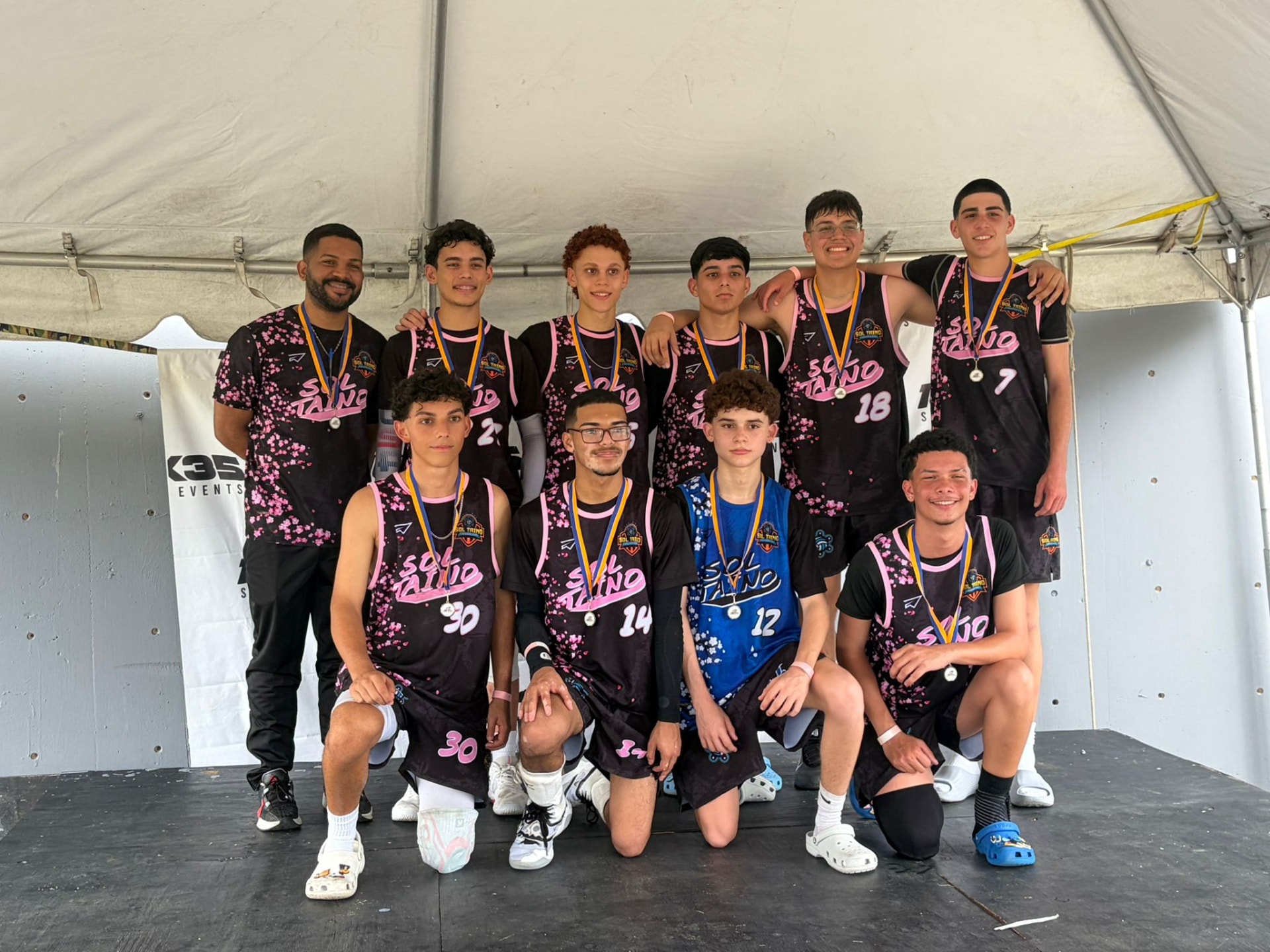 Jugadores de Sol Taíno con medallas al cuello junto a su coach tras la premiación